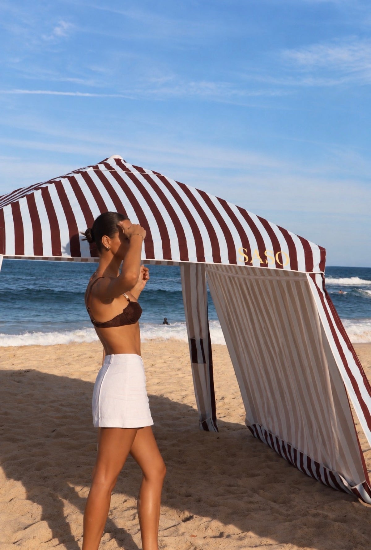 The Burleigh Cabana in brown-burgundy and pale sky blue stripes at the beach 